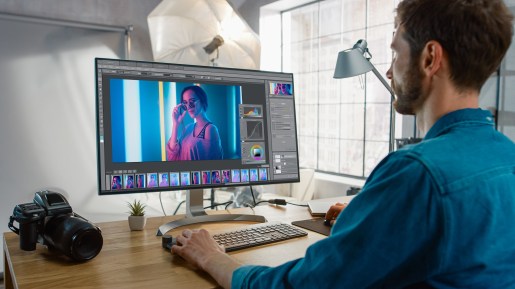 Professional Photographer Sitting at His Desk Uses Desktop Compu